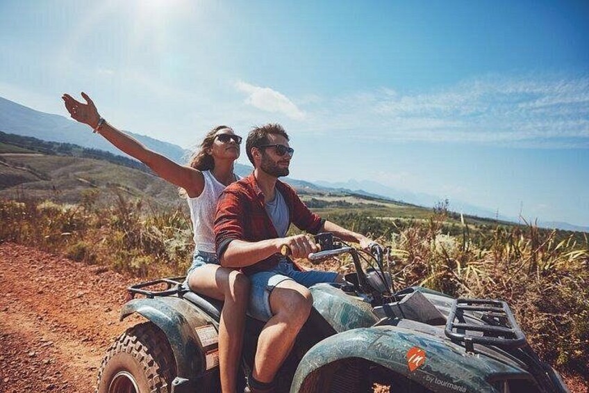Two people on a quad bike in a rural landscape with hills in the background. 5