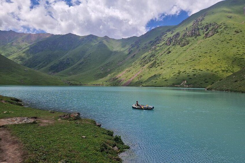 A person in a kayak on a turquoise lake surrounded by green hills. 2