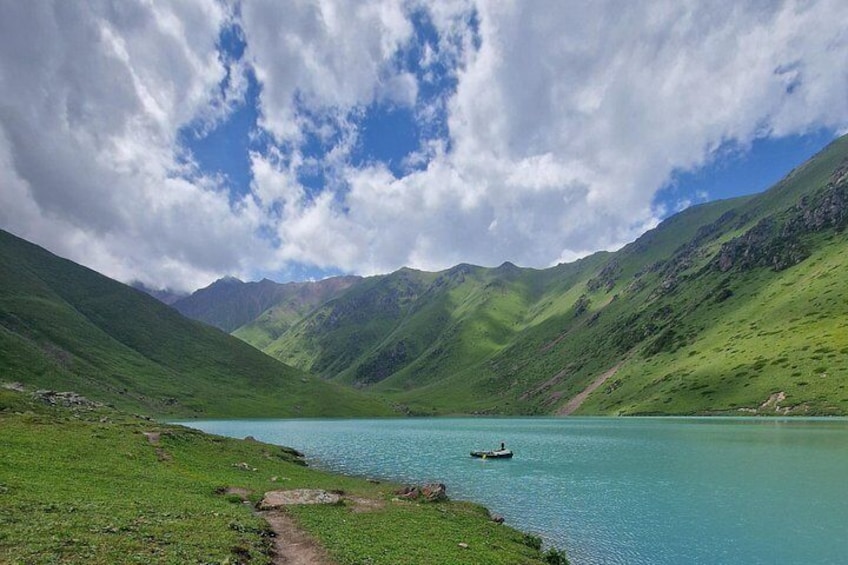 A lake surrounded by green hills under a partly cloudy sky. 3