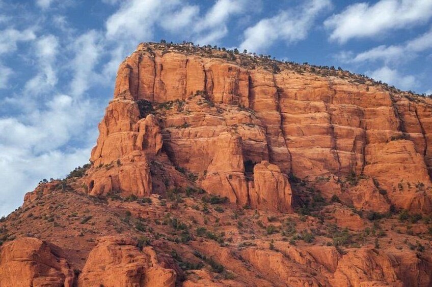 Une grande formation rocheuse rouge, avec un sommet plat et une petite ouverture qui mène à une grotte. 3