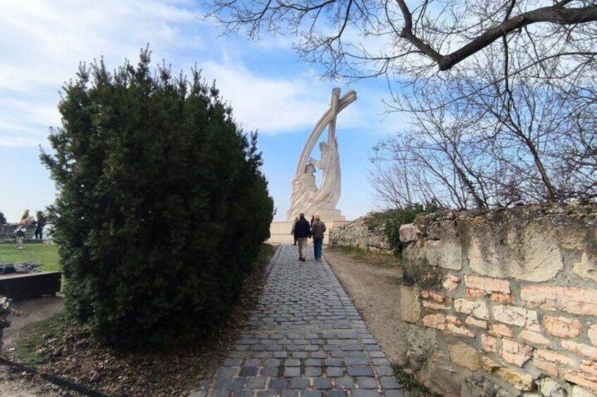 A cobblestone path, a large tree, and a sculpture in a park. 4