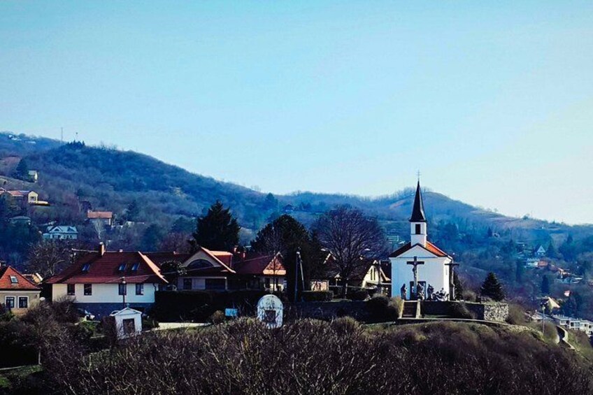 A church with a steeple, surrounded by houses and a hilly landscape. 2