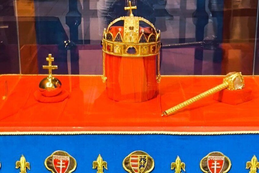 A display of a golden crown, a scepter, and a golden orb on a red velvet-covered table with a blue cloth. 5