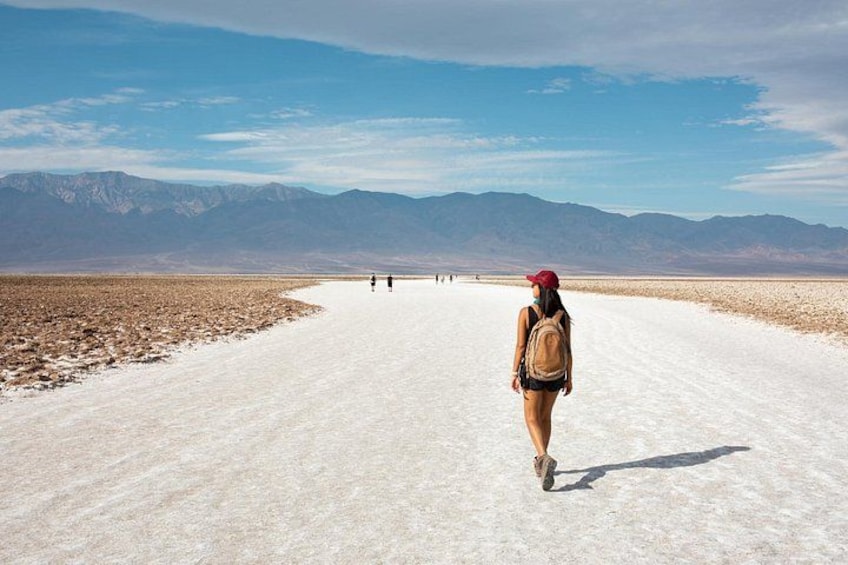 A person walking on a salt flat with mountains in the background. 1