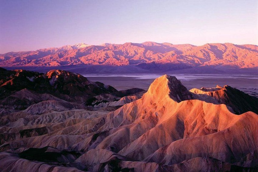 A mountainous landscape with a prominent peak in the foreground and a range of mountains in the background. 3