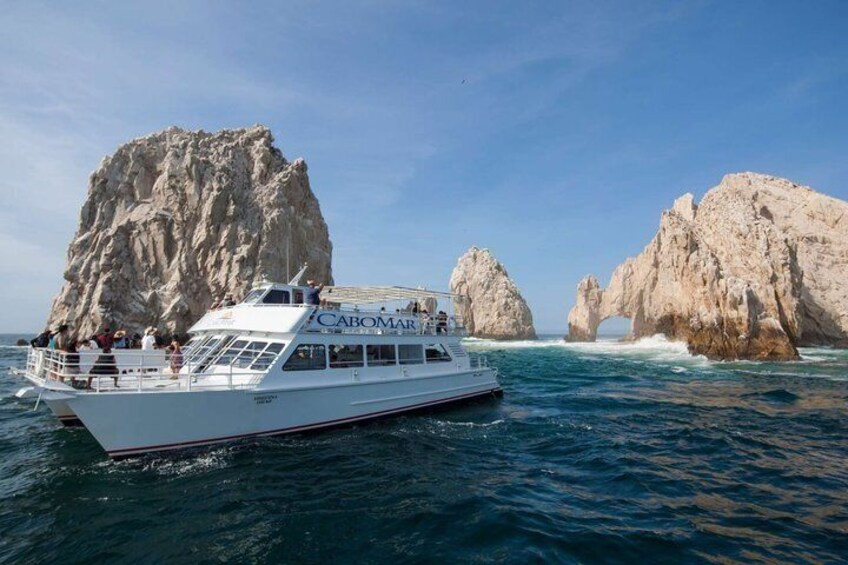Un barco llamado 'CABOMAR' con pasajeros navegando cerca de formaciones rocosas en el mar. 2