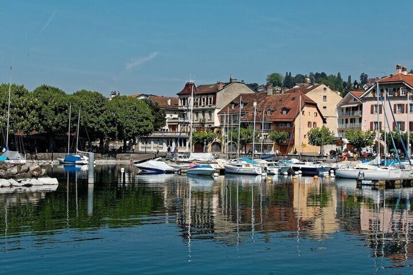 A marina with boats docked, buildings, and trees along the waterfront. 4