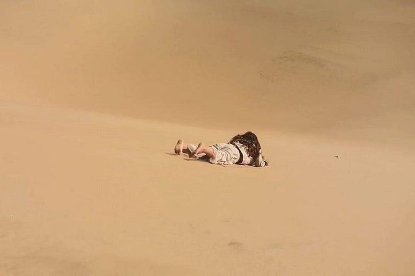 Una persona recostada en la arena en un paisaje desértico. 1