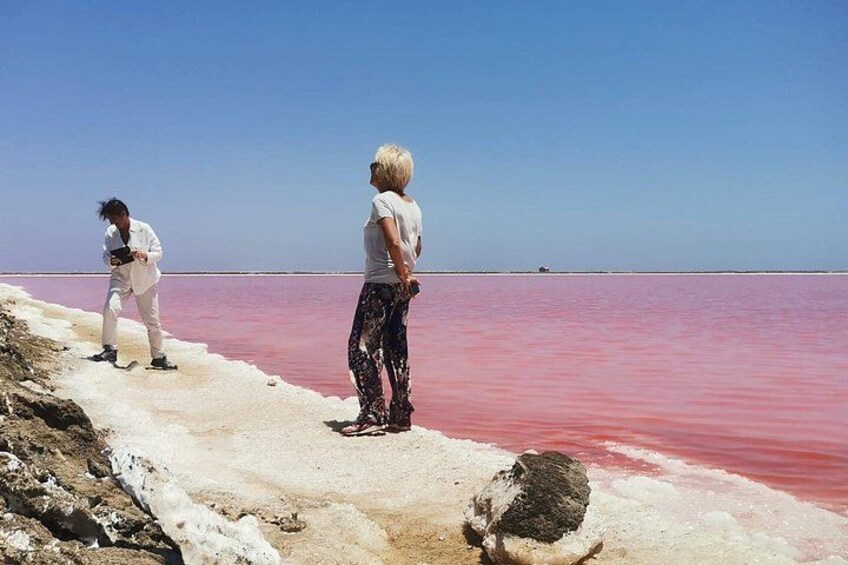 Due persone in piedi su una distesa salina con acqua rosa. 1