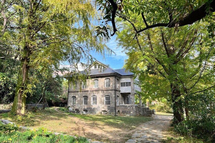 A large stone building surrounded by trees and a dirt path. 2