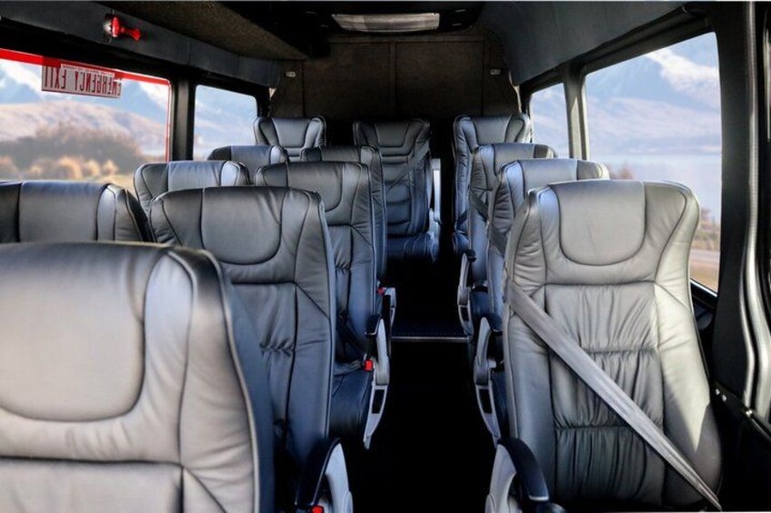 The interior of a vehicle with multiple rows of seats and a view of the outside through the windows. 5