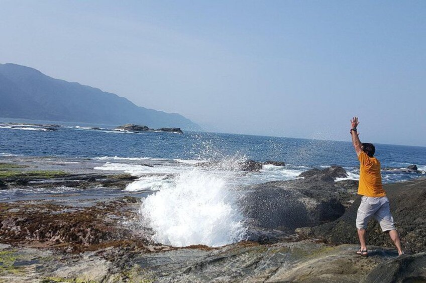 A person standing on a rocky shore with waves crashing nearby. 3