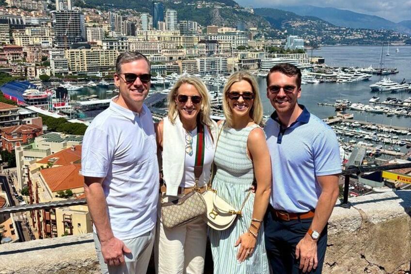 A group of people standing on a high vantage point overlooking a marina with boats and a cityscape in the background. 4