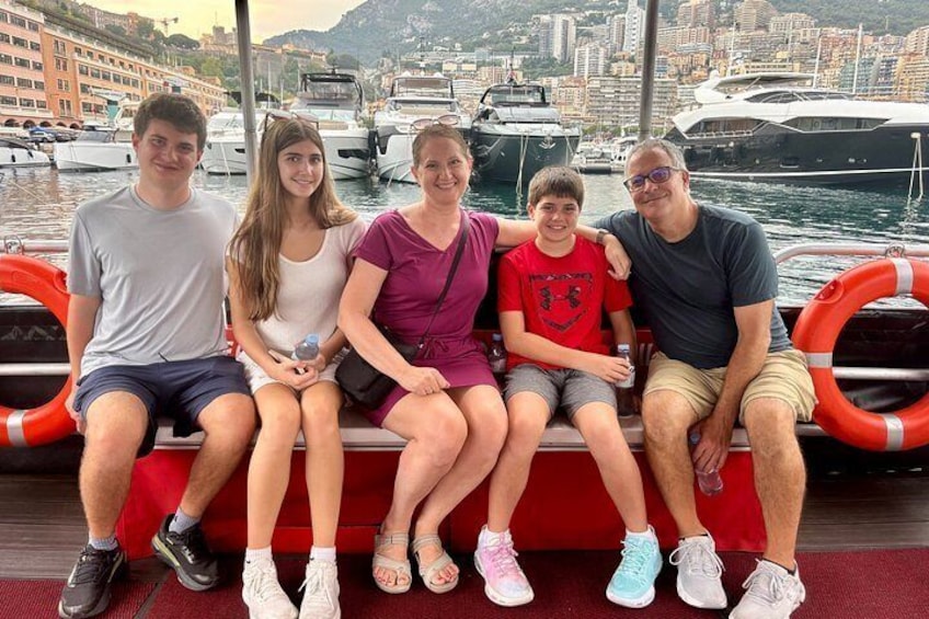 Un groupe de personnes est assis sur un bateau, avec une marina et une vue sur la ville en arrière-plan. 2