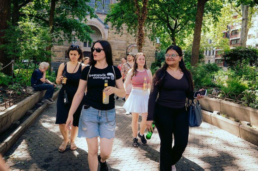 People walking on a paved path surrounded by greenery and stone structures. 3