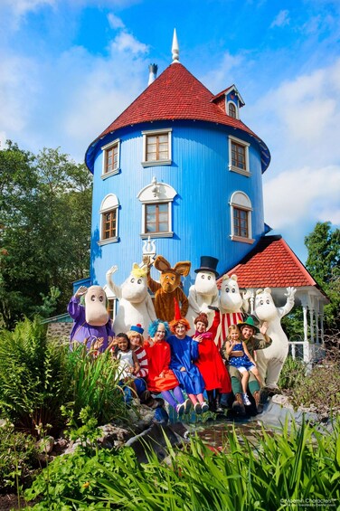 A blue house with a red roof and a group of people in front of it. 1