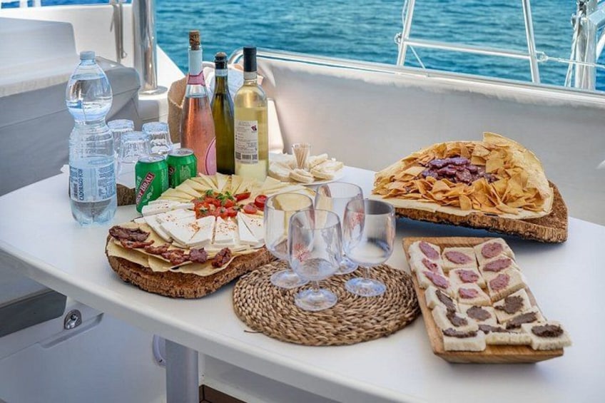 Een tafel met diverse etenswaren, flessen en glazen aan boord van een schip. 2