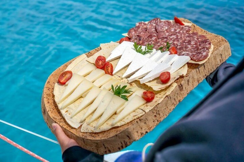 A wooden board with various cheeses and cured meats, held over a pool. 4