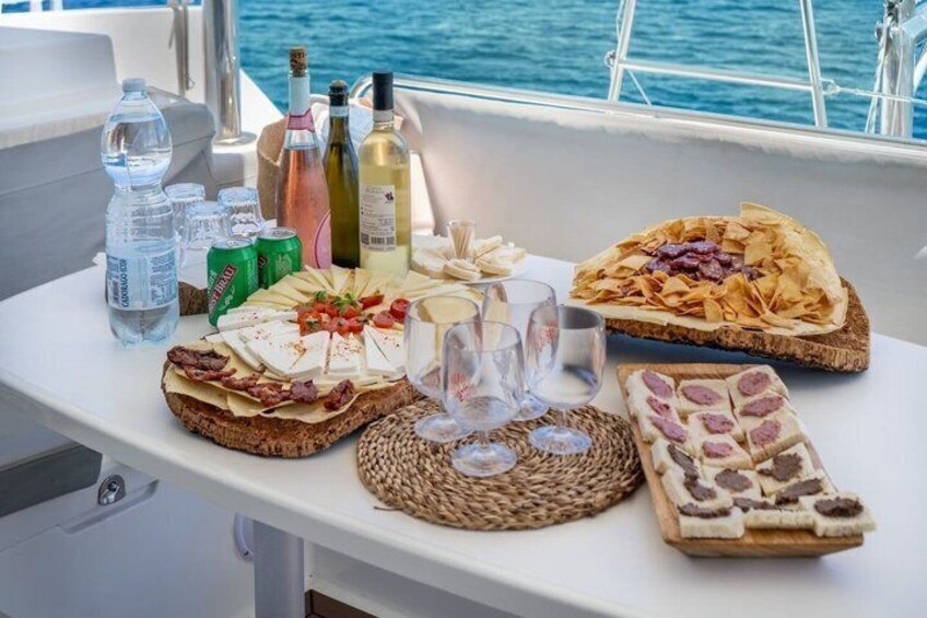 A boat deck with a table set with food, drinks, and bottles. 4