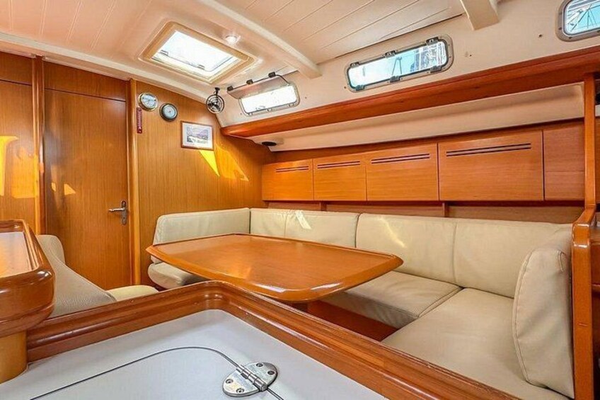 A boat interior with a wooden table, cushioned seating, and a window. 3
