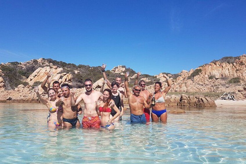 A group of people in a shallow water body with rocky cliffs in the background. 5