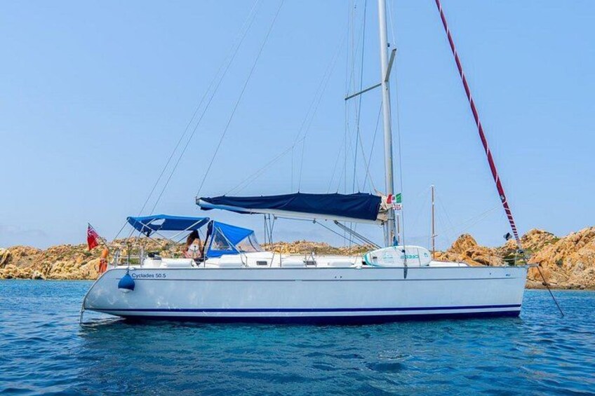 A sailboat named 'Cyclades 50.5' on calm waters with rocky coastline in the background. 1