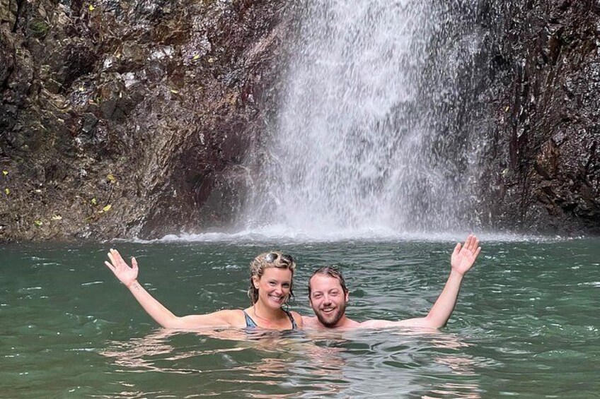 Two people in a body of water with a waterfall in the background. 3