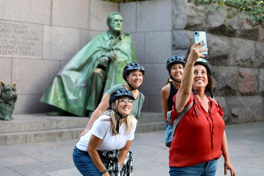 A group of people taking a selfie in front of a statue. 3