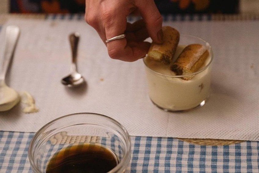 A hand dipping a pastry into a glass of liquid. 2