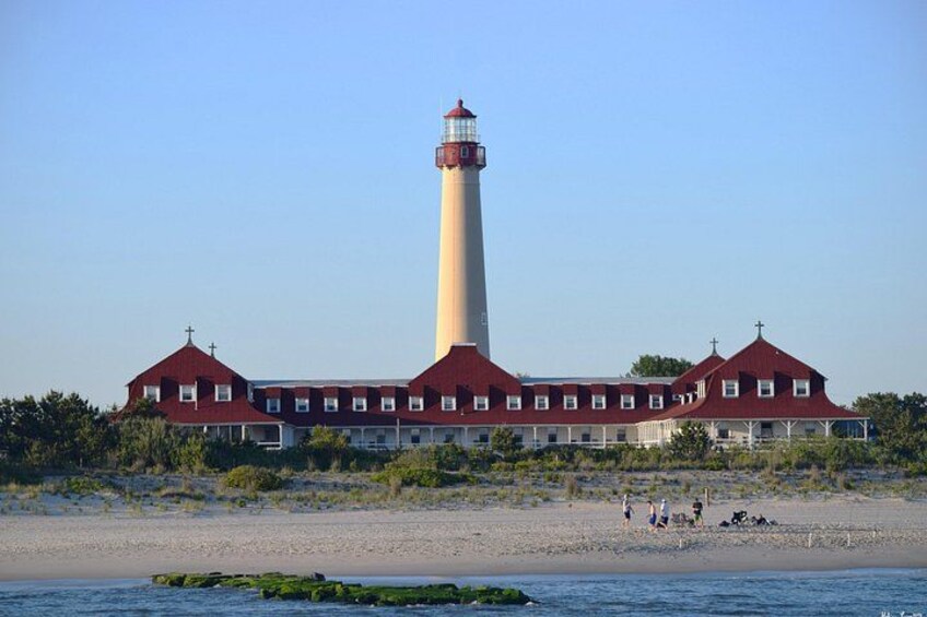Een vuurtoren met een gebouw met een rood dak, een zandstrand en een kalme zee. 3