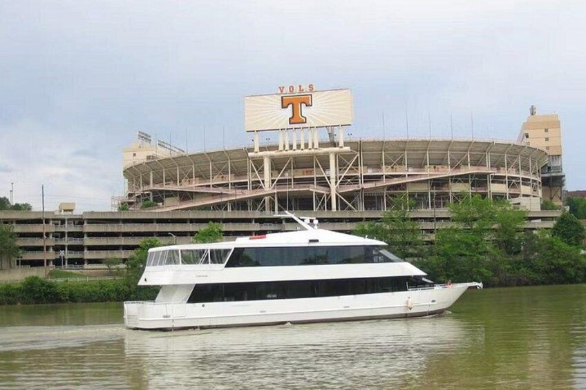 A white boat on water with a stadium in the background. 3