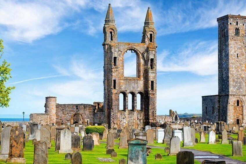 A historic stone church with a tall bell tower and multiple arches, surrounded by a cemetery with numerous headstones. 3