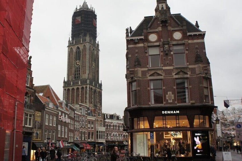 Un edificio histórico con una torre de reloj, una tienda llamada DENHAM y una concurrida escena callejera. 2