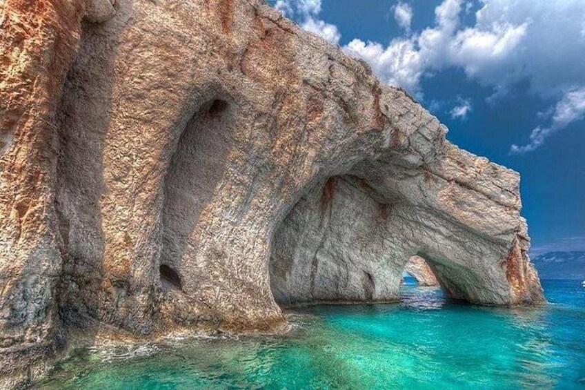 A large rock formation with a natural arch over turquoise water. 2