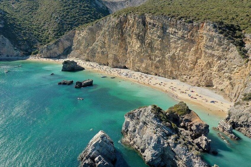 A coastal landscape with a beach, rocky outcrops, and clear turquoise waters. 4