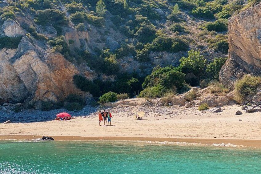 A beach with people, a red car, and rocky cliffs. 3
