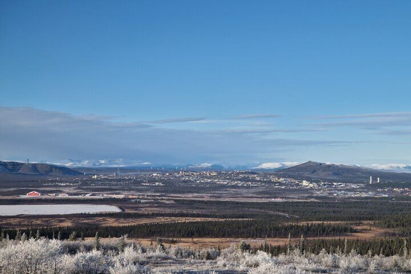 A panoramic view of a city with a river, mountains, and a clear sky. 1