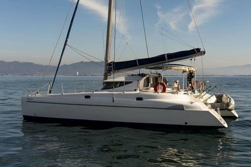 Un voilier sur des eaux calmes, avec une côte montagneuse en arrière-plan. 3