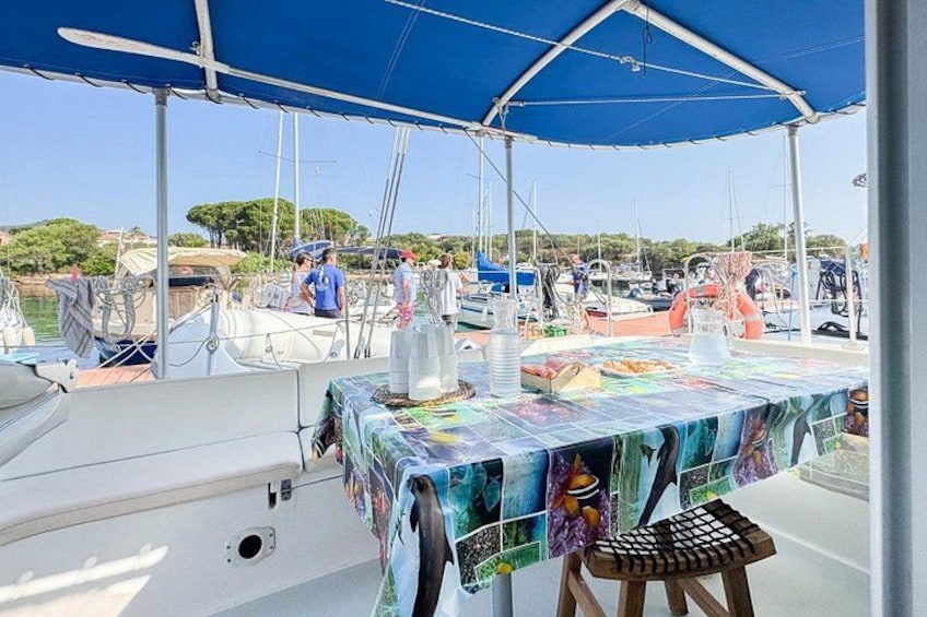 Un bateau avec une table recouverte d’une nappe colorée, entouré d’autres bateaux et sous un ciel dégagé. 2