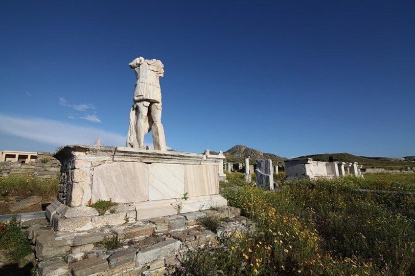 A marble statue on a pedestal in a field with scattered tombs and wildflowers. 5