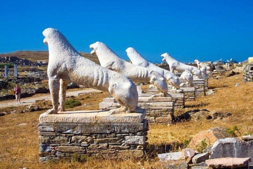 Estatuas blancas de leones de piedra sobre pedestales en un sitio histórico, con un cielo azul despejado. 5