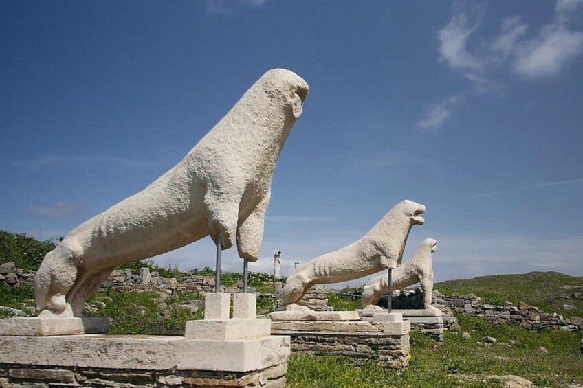 Dos estatuas blancas de leones de piedra sobre un pedestal de piedra en un césped bajo un cielo despejado. 1