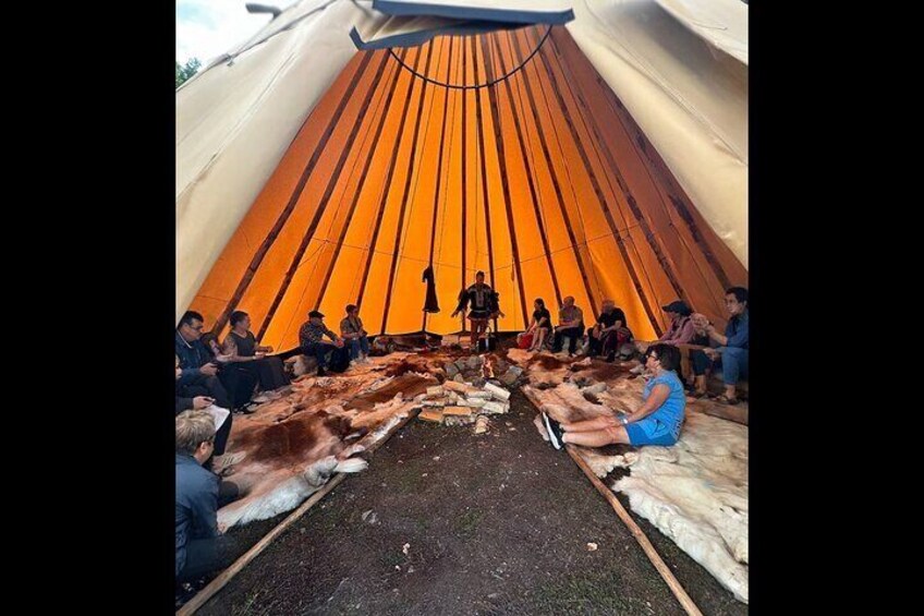 A group of people sitting inside a tent with a circular orange interior. 4