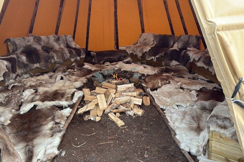 A tent with a fire in the center surrounded by animal hides. 3