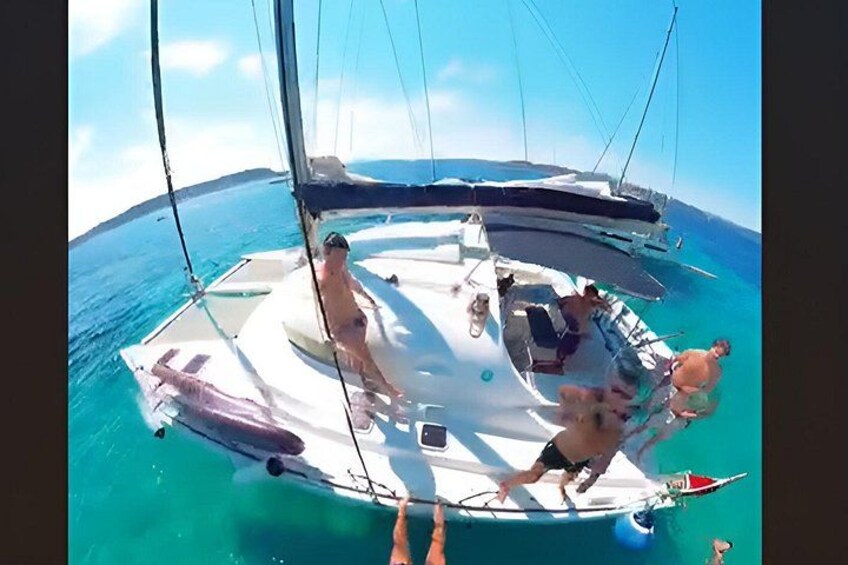 A sailboat with people on deck, calm sea, and clear sky. 2
