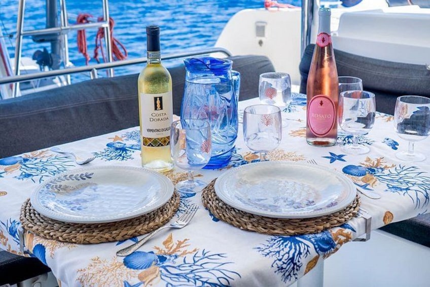 A table set for two with plates, a bottle of wine, and a pitcher on a boat. 3