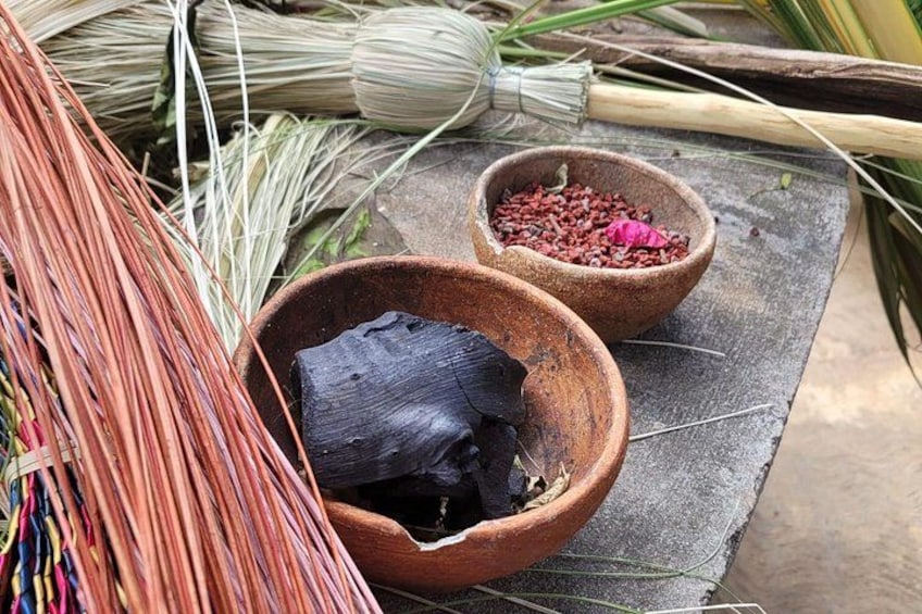 Una cesta tejida, una maceta de barro y un cuenco con granos rojos sobre un tapete. 1
