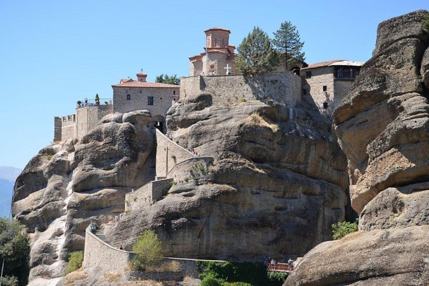 A monastery perched on a rocky cliff with a staircase leading up to it. 4