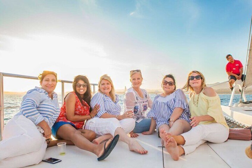 A group of people sitting on a boat deck during sunset. 2