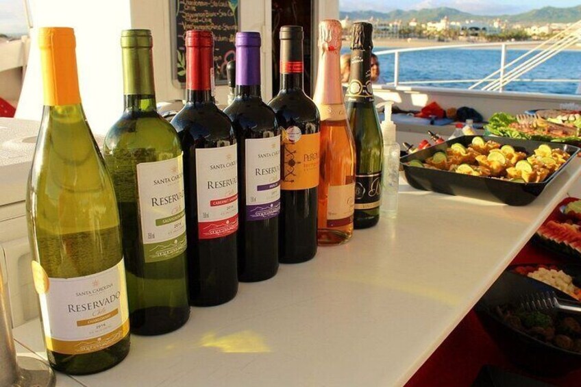 A row of wine bottles on a boat with a view of the sea and mountains in the background. 4